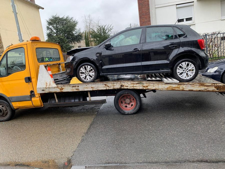 Volkswagen Polo noire sur le plateau de la dépanneuse, enlèvement sous la pluie